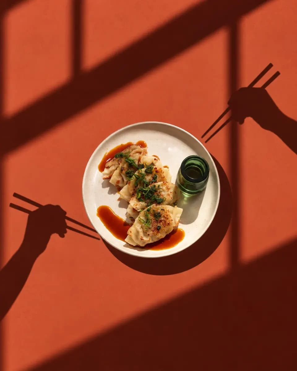 Gyozas con salsa sobre una mesa naranja en Bardana Ramen